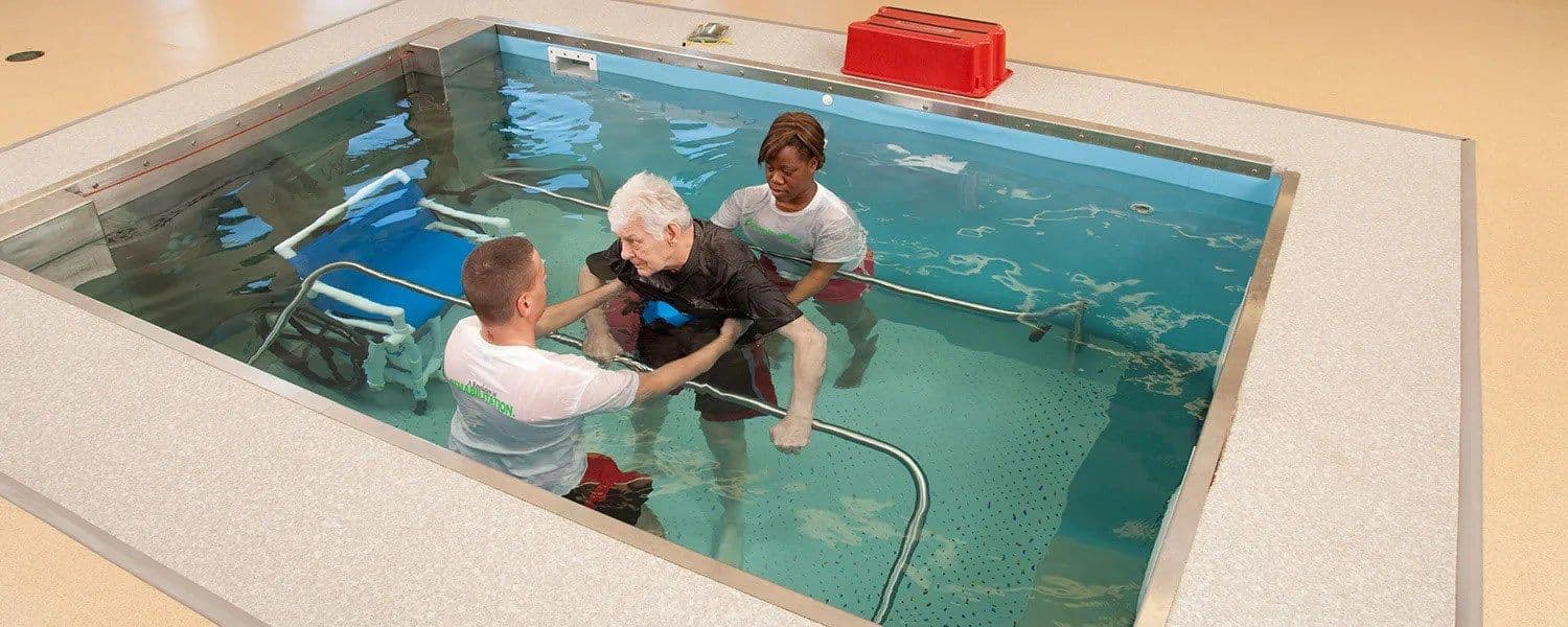 Therapists assisting a patient during a hydrotherapy session